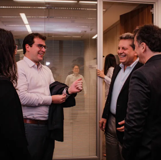 Grupo de executivos sorrindo e conversando em um ambiente corporativo