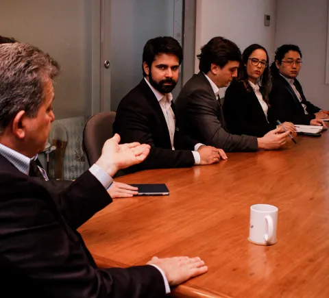 Grupo de executivos sentados ao redor de uma mesa de madeira