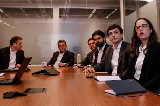 Grupo de executivos analisando apresentação ao redor de uma mesa de madeira